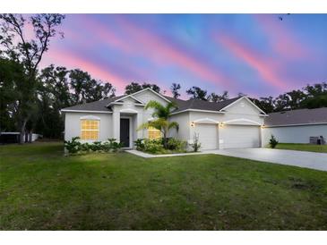 Two-story house with a three-car garage, manicured lawn, and a beautiful sunset at 606 Urick St, Fruitland Park, FL 34731