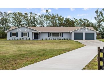 Newly renovated home with gray exterior, two-car garage, and a long driveway at 851 Marllo Rd, Kissimmee, FL 34744