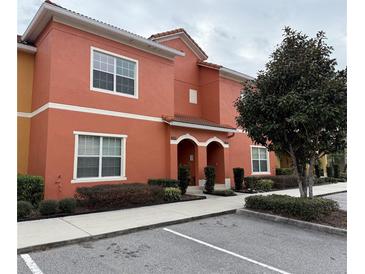 Two-story building with orange exterior, two entrances, and landscaping at 8956 California Palm Rd, Kissimmee, FL 34747
