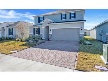 Two-story house with gray siding, brick accents, and a paver driveway at 1582 Outback W Rd, St Cloud, FL 34771