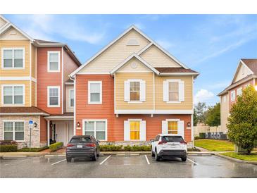 Two-story townhome with orange and beige siding, two-car parking at 2634 Sunrise Shores Dr, Kissimmee, FL 34747