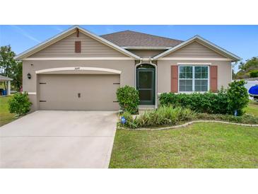 Beige house with two-car garage and landscaped lawn at 2649 Howland Blvd, Deltona, FL 32738