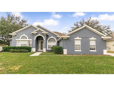 Gray one-story house with a landscaped lawn and walkway at 728 Longford Loop, Apopka, FL 32703