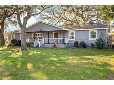 Gray house with white trim, front porch, and large yard at 860 Oak Dr, Groveland, FL 34736