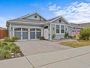 Gray craftsman style home with a three-car garage and landscaped front yard at 385 Alcove Dr, Groveland, FL 34736