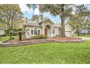 Single-story home with red door, landscaped yard, and stone wall at 926 Palm Oak Dr, Apopka, FL 32712