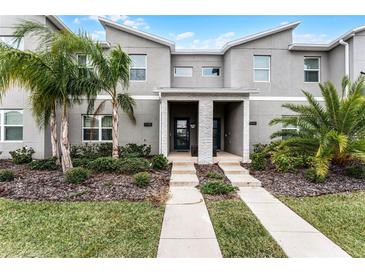 Modern two-story townhome with gray exterior, landscaping, and walkway at 1046 Splash Shot Pl, Davenport, FL 33896