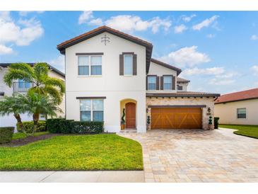 Beautiful two-story home featuring a tile roof, wood garage door, manicured lawn, and lush landscaping at 10824 Royal Cypress Way, Orlando, FL 32836