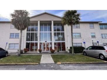 Condo building exterior with palm trees and ample parking at 1902 Honour Rd # 9, Orlando, FL 32839