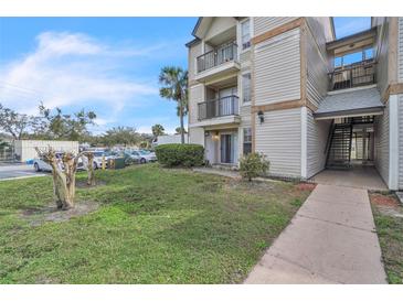 Condo exterior with balconies, stairs, adjacent parking, manicured lawn, and tropical trees against a partly cloudy sky at 1932 Lake Atriums Cir # 69, Orlando, FL 32839