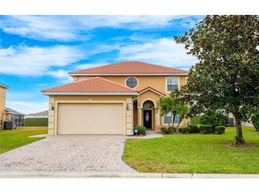 Two-story house with a beige exterior, a large garage, and a well-manicured lawn at 412 Vista Dr, Davenport, FL 33897