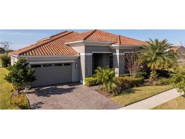 Gray house with a tile roof, driveway, and landscaping at 13370 Alderley Dr, Orlando, FL 32832