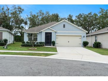 Single-story home with light blue exterior, two-car garage, and landscaped yard at 3627 Crimson Clover Dr, Mount Dora, FL 32757