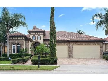 Two-story house with a brick facade, three-car garage, and landscaped front yard at 13412 Heswall Run, Orlando, FL 32832