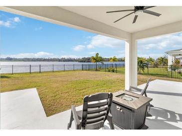 Covered patio overlooks a lake, grassy yard, and fenced-in backyard at 3032 Ella Way, St Cloud, FL 34771