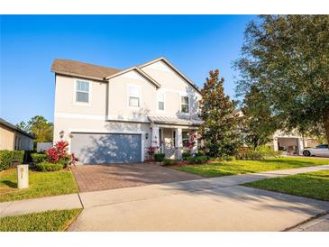 Two-story house with gray siding, paver driveway, and landscaping at 3439 Feathergrass Ct, Harmony, FL 34773