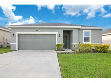 One-story house with gray siding, two-car garage, and landscaped lawn at 3482 Forster Ave, Leesburg, FL 34748