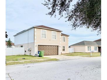 Two-story house with brown garage door and white fence at 5861 Windridge Dr, Winter Haven, FL 33881