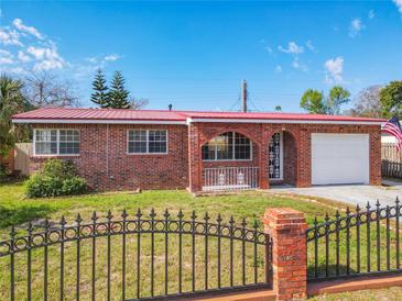 Charming brick home with a red metal roof, arched entryway, and decorative black fence at 930 Lewis Dr, Daytona Beach, FL 32117