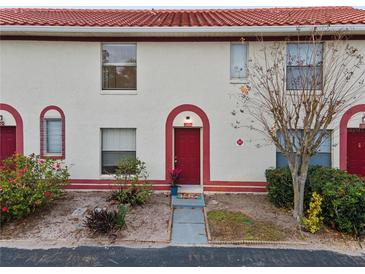 Inviting condo exterior featuring a red door and well-maintained landscaping at 1606 Sandy Point Sq # 53, Orlando, FL 32807