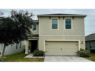 Two-story house with beige siding, two-car garage, and landscaping at 3033 Timber Hawk Cir, Ocoee, FL 34761