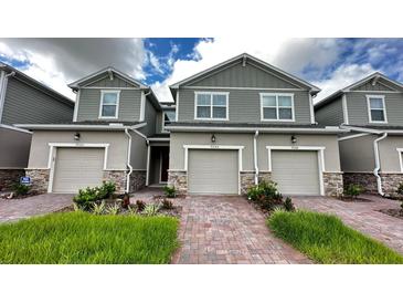 Charming townhouse featuring a well-manicured front lawn and inviting brick pathway leading to the front door at 9088 Ocean Tide Way, Kissimmee, FL 34747