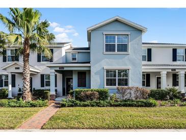 Two-story townhome with light blue exterior, brick walkway, and landscaping at 11868 Pulitzer Pl, Orlando, FL 32832