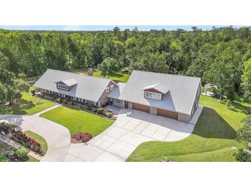 A sprawling home featuring a metal roof, lush landscaping and an expansive concrete driveway at 12788 Gillard Rd, Winter Garden, FL 34787