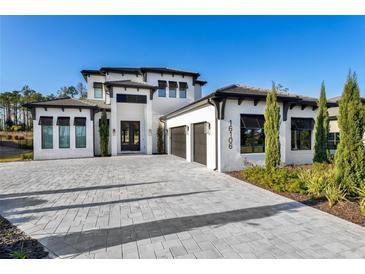 Two-story house with a three-car garage and a paver driveway at 16106 Pendio Dr, Bella Collina, FL 34756