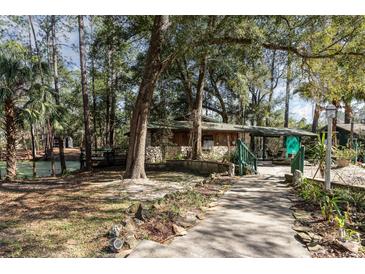 Beautiful home exterior with stone accents, a covered walkway and lush natural surroundings at 221 Se 125Th Terrace Rd, Silver Springs, FL 34488
