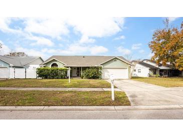 One-story house with green siding, attached garage, and landscaped yard at 1747 Lady Slipper Cir, Orlando, FL 32825