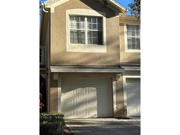 Tan two-story townhome with a two-car garage and large window at 2579 San Tecla St # 105, Orlando, FL 32835