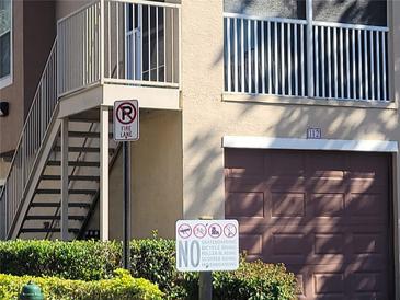 Building exterior featuring a brown garage door and second-floor balcony with metal railing at 12216 Wild Iris Way # 112, Orlando, FL 32837