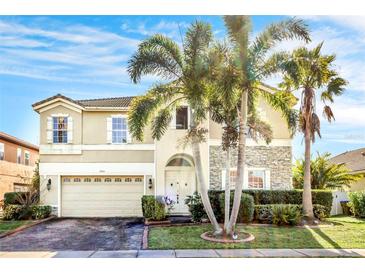 Two-story house with beige exterior, stone accents, and palm trees at 3915 Shoreview Dr, Kissimmee, FL 34744