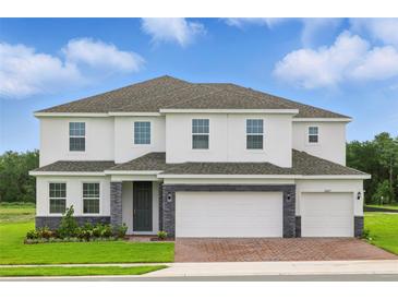 Beautiful two-story home featuring a three-car garage, landscaped yard, and a stone-accented facade at 5067 Northern Dove Ave, Mount Dora, FL 32757
