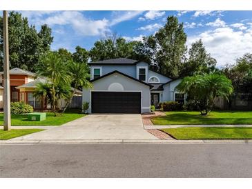 Two-story house with a gray exterior, black garage door, and landscaped yard at 749 Silver Birch Pl, Longwood, FL 32750