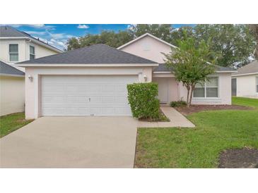 Cute pink house with a white garage door and well-maintained lawn at 120 Casterton Cir, Davenport, FL 33897