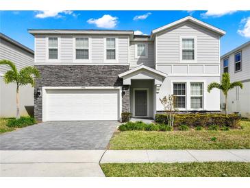 Two-story house with gray siding, stone accents, and a two-car garage at 1986 Summer Dr, Davenport, FL 33897