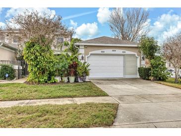 Tan house with white garage door, landscaping, and driveway at 3264 River Branch Cir, Kissimmee, FL 34741