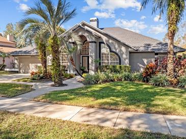 Beautiful home with a well-manicured lawn and mature palm trees at 6541 Fairway Hill Ct, Orlando, FL 32835