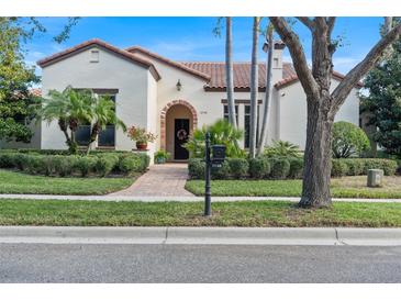 Mediterranean-style home with tile roof, lush landscaping, and a brick walkway at 11748 Waterstone Loop Dr, Windermere, FL 34786