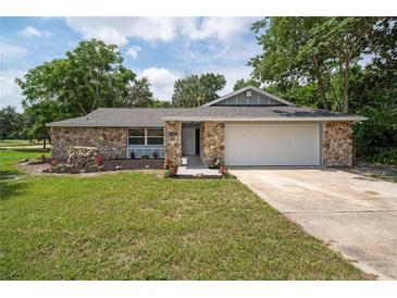 Charming stone front house with gray roof and landscaped yard at 1365 Indian Rock Ct, Deltona, FL 32725