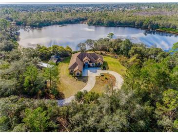 Luxury home on a lake with circular driveway, surrounded by lush greenery at 1851 Grand Keahl Ln, Deltona, FL 32738