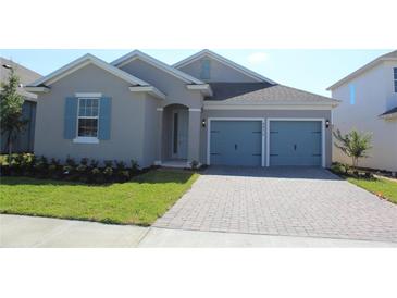 Gray house with blue doors and a paved driveway at 4476 Lions Gate Ave, Clermont, FL 34711