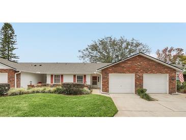 Brick front exterior of a two-unit home with two-car garage and landscaped lawn at 5132 Lazy Oaks Dr # 5132, Winter Park, FL 32792