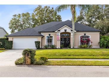 Tan one-story house with a gray roof, palm tree, and manicured lawn at 623 Yorkshire Dr, Oviedo, FL 32765