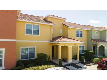 Bright yellow two-story house with a covered entryway and well-manicured landscaping at 3045 Beach Palm Ave, Kissimmee, FL 34747