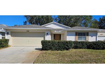 One-story house with beige siding, attached garage, and manicured lawn at 32712 Timberwood Dr, Leesburg, FL 34748