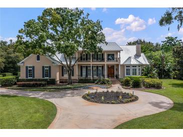 Two-story house with metal roof, circular driveway, and landscaped lawn at 3413 Lilas Ct, Windermere, FL 34786