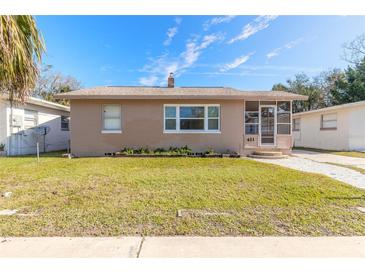 Tan single story home with landscaped lawn, walkway and screened porch at 421 Jefferson St, Daytona Beach, FL 32114